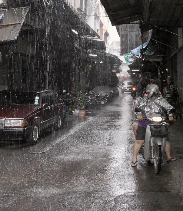 A lane in heavy rain, figures moving under cover