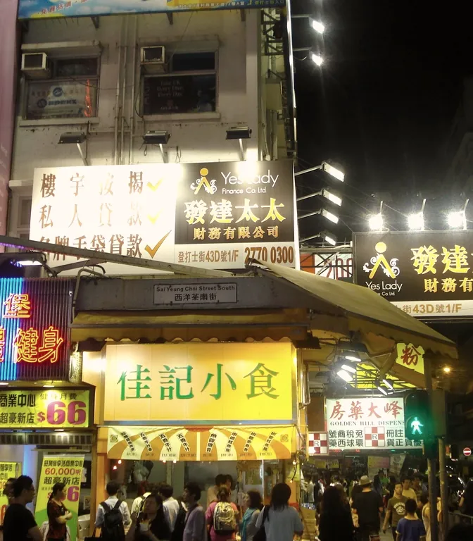 Illuminated shop signs stacked above a night street