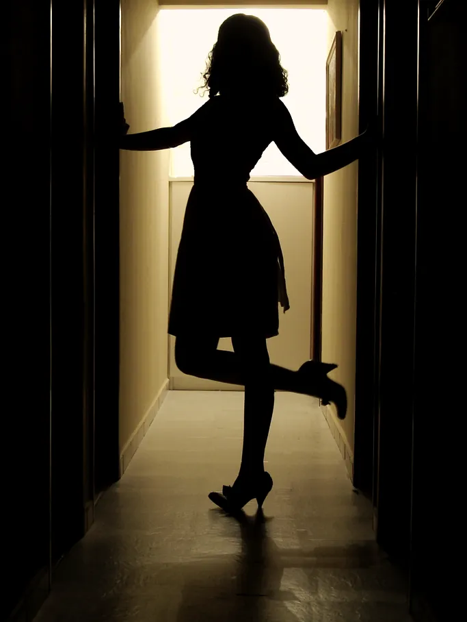 A figure silhouetted in a lit doorway