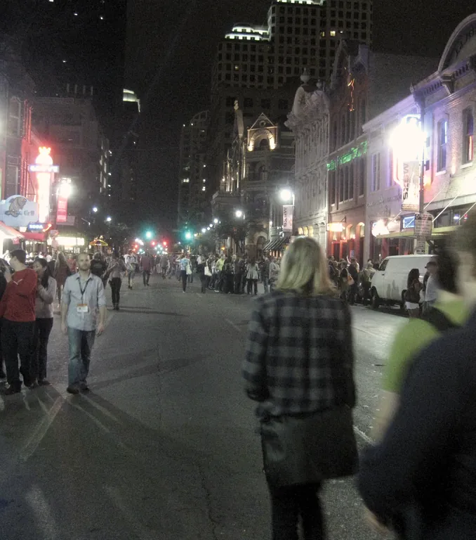 A crowd on a neon-lit street after dark