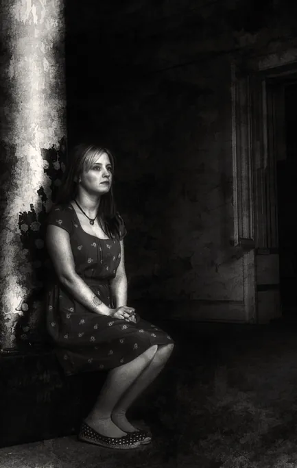 A seated figure in an empty room, monochrome
