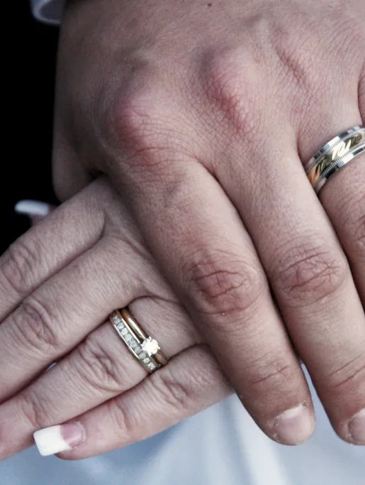 Two hands resting together, wedding rings visible